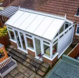 Aerial view of a white conservatory with a solid panelled roof attached to a brick house